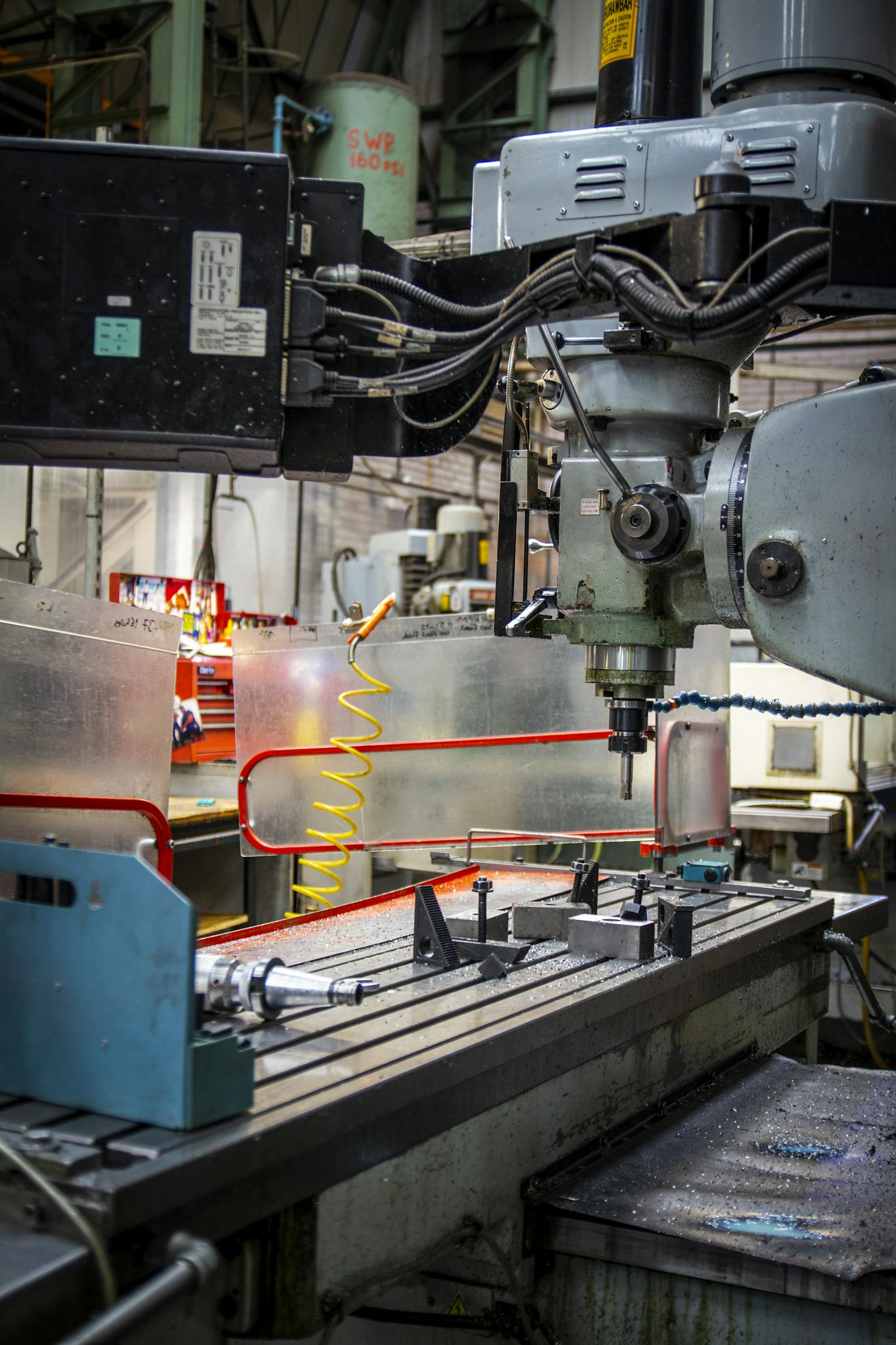 Close-up of an industrial CNC lathe in a bustling machine shop setting, focused on precision metalwork.