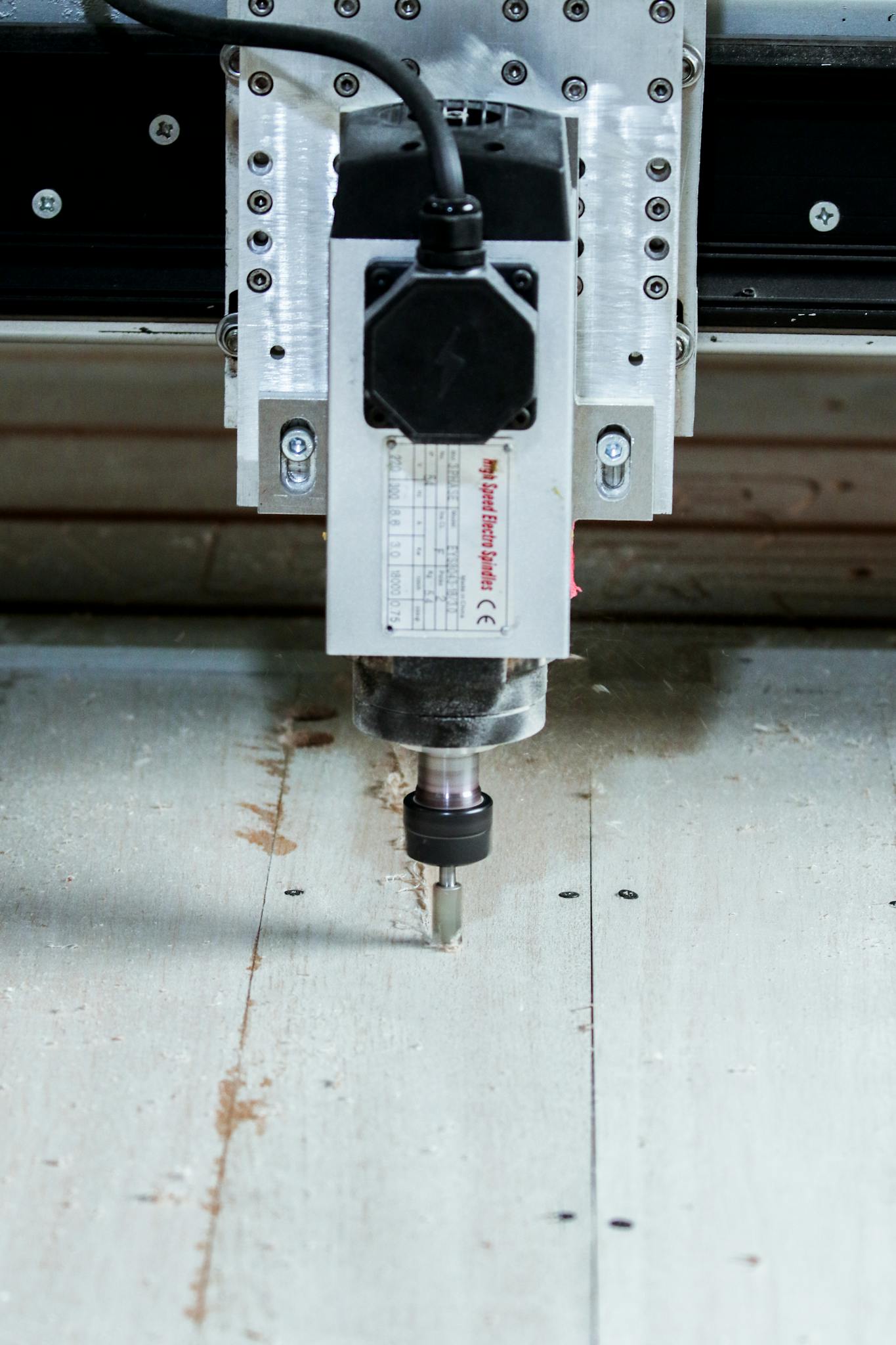 High-precision CNC milling machine working on a wood panel in an industrial workshop setting.